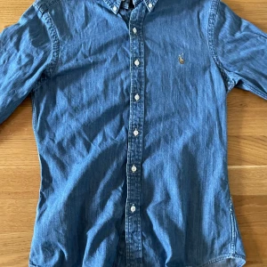 Blå Ralph Lauren Skjorta - Snygg blå jeansskjorta från Polo Ralph Lauren i slim fit. Klassisk design med knappar framtill och broderad logga på bröstet. Skriv för frågor!
