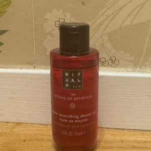 Rituals The Ritual of Ayurveda duscholja - Röd flaska med ultra nourishing shower oil från Rituals, The Ritual of Ayurveda. Innehåller mandelolja och indisk ros, 75 ml. Oljan ger en lyxig känsla och doftar fräscht. Perfekt för dig som vill ha en återfuktande duscholja med spa-vibbar.