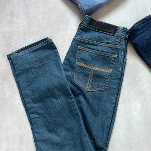Blå jeans från Tiger of Sweden - Klassiska blå jeans från Tiger of Sweden 👖 Raka ben, fem fickor & snygga gula sömmar 🟫 Stilren läderpatch bak i midjan 📏 Storlek: 32/32 💯 Skick: Mycket bra (9/10) 💸 Orginalpris: ca 1500kr  Perfekta för dig som gillar en tidlös & clean look. 📩 Skicka DM vid intresse eller frågor! 