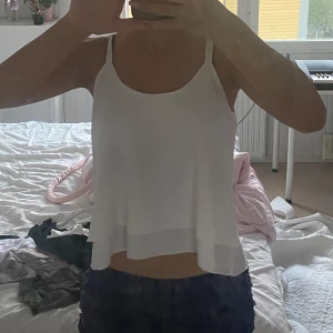 Vit flowy linnetopp med tunna band - Säljer en vit, luftig linnetopp med tunna axelband och dubbla lager tyg. Toppen har en lös och flowy passform som ger en chill vibe och är perfekt för varma dagar. Enkel och stilren design som är lätt att matcha med allt.
