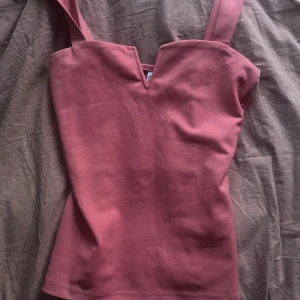 Rosa linnetopp från Chiara Fortel XS - Supersnygg rosa linnetopp från Chiara Fortel Milano i storlek XS. Toppen har breda axelband och en cool v-formad urringning framtill. Materialet känns mjukt och stretchigt, perfekt för att lyfta vilken outfit som helst.