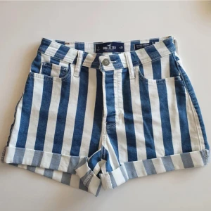 Shorts från Hollister - Snygga högmidjade shorts från Hollister med breda blå och vita ränder. Klassisk jeansmodell med fem fickor, uppvikta benslut och bälteshällor. Aldrig använda!                                                                         Hör av dig vid frågor! Köparen står för frakten. 