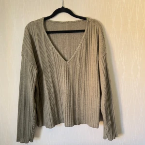 Grön  ribbad v-ringad tröja - Ribbad hrön tröja  i storlek M. Tröjan har v-ringning, lång ärm och en loose fit som ger en chill vibe. Perfekt för lager-på-lager och funkar till både jeans och kjol. Materialet är mjukt och stickat för extra komfort.