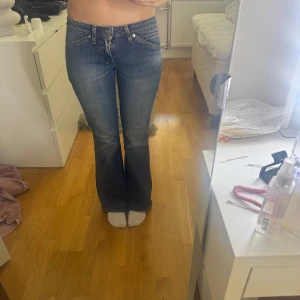 Lågmidjade jeans - Snygga blå bootcut jeans från Levis med klassisk femficksdesign och lätt slitna detaljer. Jeansen har låg midja och är tillverkade i mjuk denim med en skön passform. Perfekta för dig som gillar en retro vibe och vill ha ett par jeans som sticker ut.