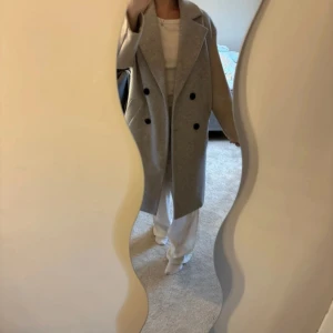 Grå-beige kappa från Bershka - Säljer en snygg kappa från Bershka i grått och beige. Oversized fit med dubbelknäppning och stora slag. Perfekt för höst och vinter, tillverkad i ullblandning. Långärmad och stilren, passar till allt och ger en clean vibe.