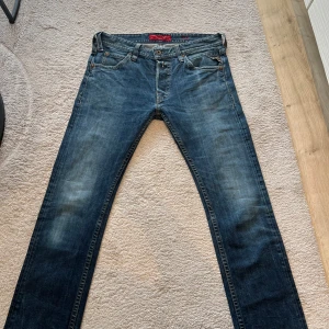Replay jeans i blå denim, stl 34 - Säljer ett par klassiska blå jeans från Replay i storlek 34. Jeansen har snyggt slitna detaljer, raka ben och femficksmodell. Bakfickorna har dekorativa sömmar och märkeslogga. Perfekta för en avslappnad och stilren look.W34 L34 mycket fina och är slim fit, använda  ganska lite