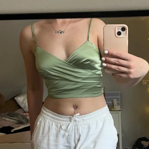 Grön satin topp - Fin satin topp med knyte i ryggen, passar både XS och S eftersom man knyter själv. Endast använd vid ett tillfälle