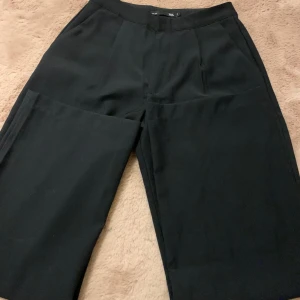 Svarta kostymbyxor från 157, stl S - Endast använda ett få antal gånger och har inga tecken på användning. Svarta kostymbyxor från 157 med klassisk rak passform och pressveck framtill. Byxorna har fickor i sidorna och en diskret bakficka. Midjan är midwaist men kan staylas olika beroende på person till person. (Kan användas som lowwaist och midwaist)