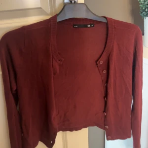 Vinröd kofta från 157, XS - Säljer en vinröd kofta från 157 i storlek XS. Koftan har långa ärmar, ribbad kant vid halsen och knäppning framtill med flera knappar. Perfekt att slänga över en topp för en chill look.