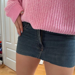 Jeanskjol från Divided, stl 38 - Mörkblå jeanskjol från Divided i klassisk denim med rå kant nertill. Modellen är kort och har hög midja, dragkedja och knapp framtill samt fickor både fram och bak. Perfekt för dig som gillar en enkel och snygg stil. Från början var det ett par jeans, men jag har klippt de till ett par shorts!