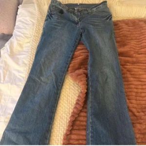 Blå bootcut jeans med broderi - Snygga blå jeans med bootcut passform och broderade detaljer på bakfickorna. Jeansen har klassisk femficksdesign, normal midja och är tillverkade i denim. Perfekta för dig som gillar en lite mer unik look med coola detaljer. Midje måttet är ca 35/36cm och innerbenslängden är 76cm
