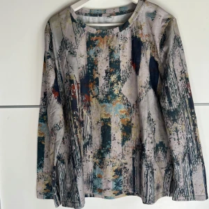 Mönstrad långärmad tröja 3XL - Säljer en långärmad tröja i storlek 3XL med abstrakt mönster i blått, beige, orange och grått. Tröjan har rund halsringning och är tillverkad i ett mjukt, stretchigt material som känns skönt mot huden. Perfekt för dig som gillar unika prints och bekväma plagg.