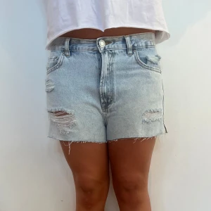 Ljusblå ripped jeansshorts - Snygga ljusblå jeansshorts med slitna detaljer. Shortsen är knappt använda och därför i väldigt bra skick. Hör av dig vid fler frågor eller funderingar!
