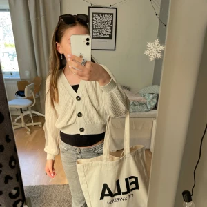 Beige stickad kofta med knappar - Storleken är 134/140 men passar mig som bär xs/s!Snygg beige stickad kofta med v-ringning och tre  svarta knappar framtill. Modellen är croppad med breda muddar och ballongärmar, perfekt att slänga över ett linne eller t-shirt. Säljer eftersom jag har 3 stycken! ❣️