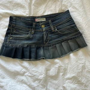 Levi's jeanskjol med volanger - Supersöt mörkblå jeanskjol från Levi's med volangkant nedtill och klassiska fickor fram och bak. Midjemått ca 36 rakt över. Hör av dig vid funderingar!🩷