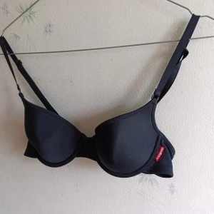 3-pack bh-topp i svart, orange, grå - Säljer tre bh-toppar från Mangon i i olika färger: en svart, en orange ribbad och en ljusgrå. Alla har justerbara axelband och vadderade kupor för extra komfort. Perfekta under en t-shirt eller linne för en enkel och snygg look.