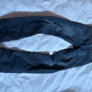 Mörkblå Slim Straight jeans Jack & Jones - Snygga mörkblå jeans från Jack & Jones, modell Slim Straight Tim. Klassisk femficksdesign, orange detaljer på insidan och kontrastsömmar. Perfekta för dig som gillar en rak men ändå smal passform. Materialet är klassisk jeansbomull.