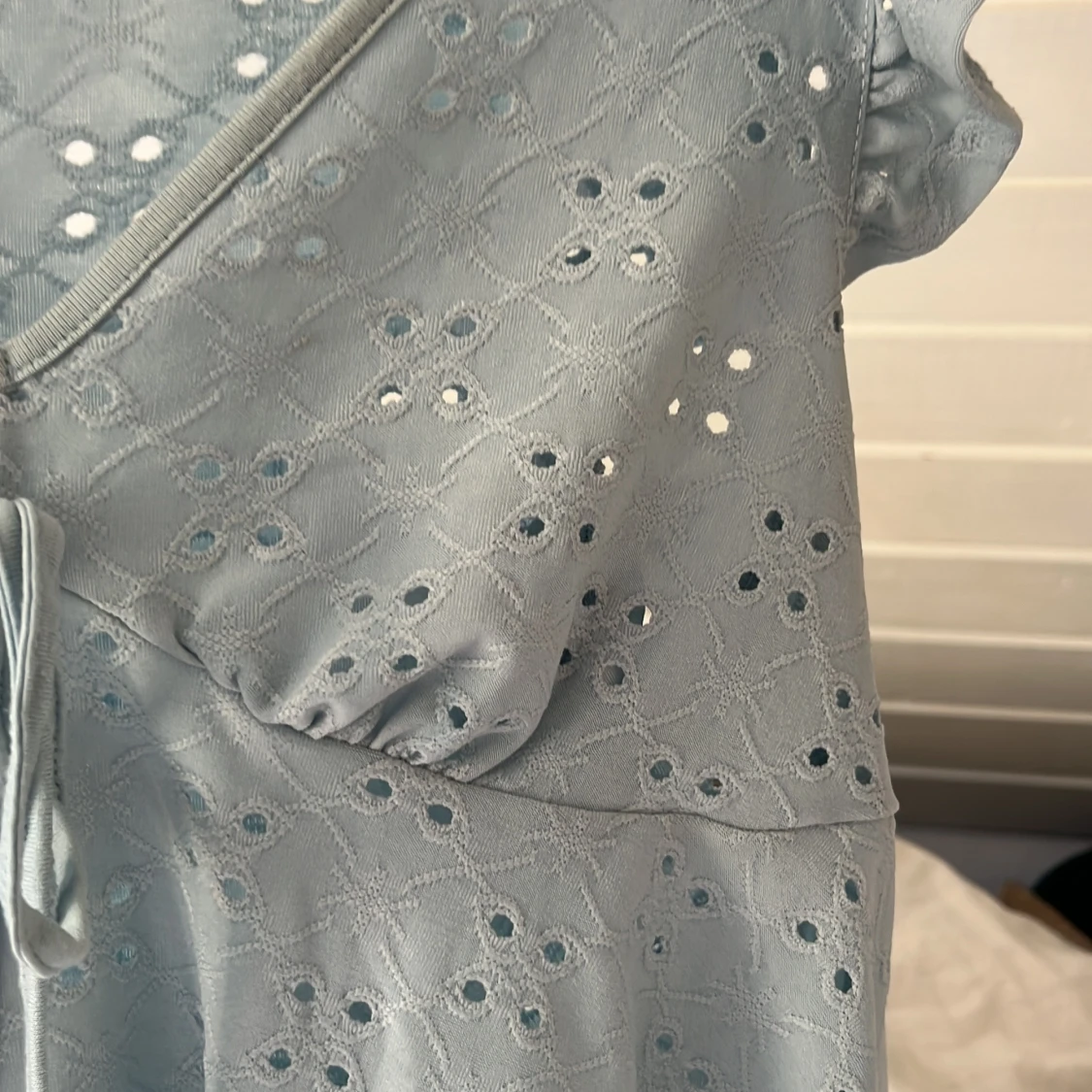 Ljusblå blus med broderade hål och volang - 1