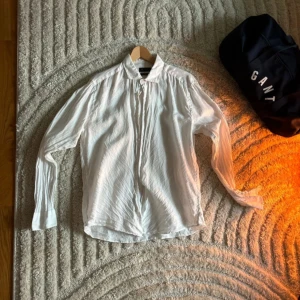 Vit linneskjorta från Riley slim fit - Snygg vit skjorta från Riley i slim fit-modell, tillverkad i svalt linne. Skjortan har klassisk krage, långa ärmar och knappar framtill. Perfekt för dig som gillar en clean och fräsch stil med lite extra edge tack vare linnets struktur.