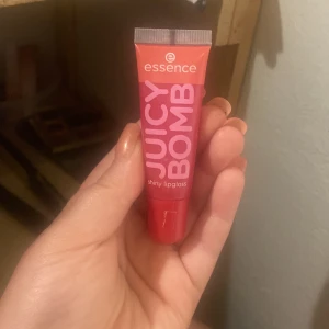 Essence Juicy Bomb Lipgloss Poppin' Pomegranate - Essence Juicy Bomb shiny lipgloss i färgen 104 Poppin' Pomegranate. Kommer i en smidig tub med skruvkork. Ger en glansig finish och har en fräsch rödrosa ton. Perfekt för att boosta läpparna med extra glans och en hint av färg.
