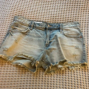 Ljusblå jeansshorts från Zara - Säljer ett par jättefina ljusblå jeansshorts från Zara med slitna detaljer och fransig kant. Säljer då de inte kommer till användning. 