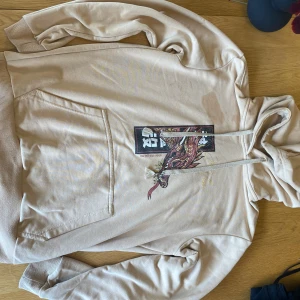 Beige hoodie med draktryck och huva - En beige hoodie med draktryck och asiatiska tecken på framsidan. Mycket bekvämt material och coola trendig design. 