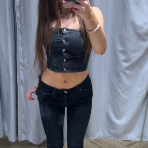 Svart croppad jeans tubtopp - Säljer en svart croppad tubtopp i jeansmaterial med knappar framtill. Toppen är axelbandslös ifrån hm i storlek xs. Kommer inte till användning därav priset❤️