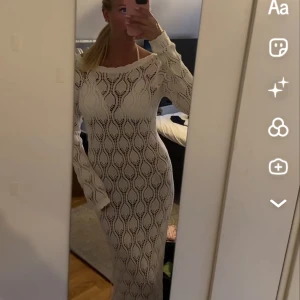 Vit lång stickad klänning med mönster - Säljer en lång, vit stickad strand klänning med vågigt hålmönster och lång ärm. Klänningen har en figurnära passform och offshoulder-ringning, perfekt för sommarens alla tillfällen. Superfin att styla med sandaler eller sneakers!