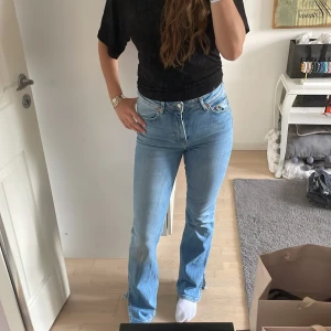 Ljusblå bootcut jeans med slits från lager 157 - Säljer ett par ljusblå jeans med bootcut passform och snygg slits nertill vid benslutet. Jeansen har hög midja och klassisk femficksdesign. Tillverkade i jeansmaterial som känns både mjukt och slitstarkt. Perfekta för dig som gillar en retroinspirerad look.