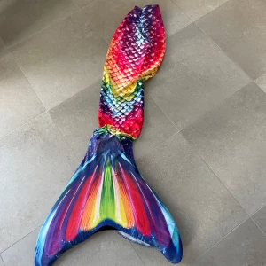 Färgglad sjöjungfrudräkt - Säljer en fantastisk sjöjungfrudräkt i regnbågens alla färger. Dräkten har ett fiskfjällsmönster och en imponerande fena i blått, rött, gult och grönt. Perfekt för att simma som en riktig sjöjungfru!