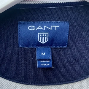 Nyskick! Grå sweatshirt från GANT - Säljer en stilren grå sweatshirt från GANT i storlek M. Tröjan är tillverkad i en mjuk bomullsblandning och har långa ärmar. Perfekt för en avslappnad look. Tror aldrig den har använts, möjligen 1ggr. Ser så gott som ny ut. Tyvärr blivit liggande i garderoben och nu för liten. Fler bilder kan fås vid intresse. Nypris 699;-