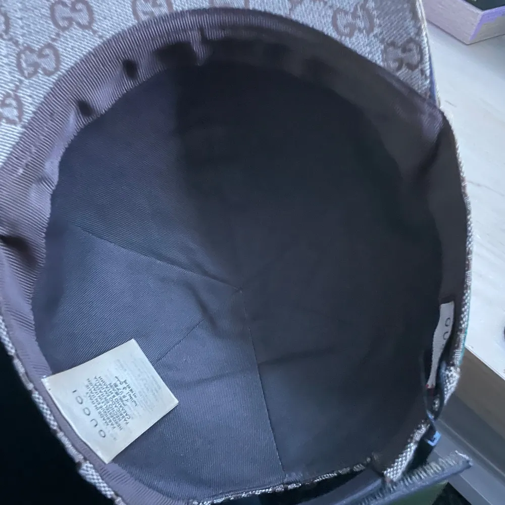 Snygg beige keps från Gucci med det ikoniska GG-mönstret. Kepsen har en klassisk design med en justerbar rem baktill och detaljer i grönt och rött på sidan. Perfekt för att ge din outfit en lyxig touch.. Asusteet.