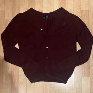 Vinröd kofta / Cardigan från Fred Perry - Säljer en vinröd kofta / cardigan från Fred Perry. Nypris är 1800kr. Koftan är liten i sin storlek och passar M. Pris kan diskuteras, skriv vid funderingar!