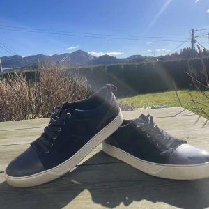 Blå sneakers från Lanvin - Snygga blå sneakers från Lanvin med vita sulor och snörning. Skorna har en rund tå och är tillverkade i skinn med detaljer i mocka. Perfekta för en stilren look.