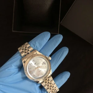 Silverfärgad klocka med metallarmband - Elegant silverfärgad klocka med ett stilrent metallarmband och en klassisk urtavla. Perfekt för den som vill ha en tidlös accessoar.