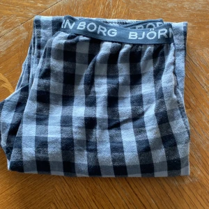 Rutig byxa från Björn Borg - Säljer ett par bekväma rutiga byxor från Björn Borg. Byxorna har en elastisk midja med Björn Borg-logga och ett klassiskt rutmönster i svart och grått. Perfekta för en avslappnad stil.
