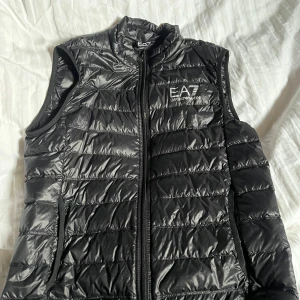 Svart dunväst från EA7 - Snygg svart dunväst från EA7. Väldigt fräsh knappt använd är en L men sitter som M