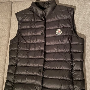 Svart dunväst från Moncler - Säljer nu min super snygga moncler väst, som jag inte använder längre tyvärr! Köpt 2022 men är i nyskick! Storleken är 3 men har vanligtvis s/m och den passar mig super. Äkthetsbevis medkommer, pris kan diskuteras!!