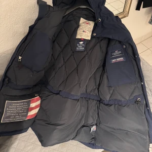 Blå Lexington Ranger Down Parka - Säljer en blå Lexington Ranger Down Parka med quiltad insida och vattenavvisande yta. Jackan har en hög krage, dragkedja och flera praktiska fickor. Perfekt för kyliga dagar.löstagbar päls på luvan 