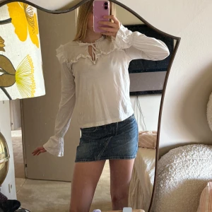 Vit blus från Odd Molly - Säljer en söt vit blus från Odd Molly med volangdetaljer och knytning vid halsen. Blusen har långa ärmar och en romantisk stil. Perfekt för en avslappnad men stilfull look. Orginalpris är 800 därav priset då varan är i gott skick.