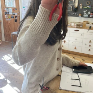  kofta med knappar + en glad chey!! - Säljer en mysig beige kofta med knappar framtill. Koftan har långa ärmar och ribbade muddar vid ärmslut och nederkant. Perfekt för en avslappnad stil.