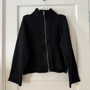 Svart stickad kofta med dragkedja - Svart stickad tröja med dubbel dragkedja från Lager 157. Använd ett fåtal gånger. Nopprig då det material den är gjort av ofta blir det men går att åtgärda. Normal i storlek.