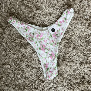 Even higher bikiniunderdel - Blommig bikiniunderdel med hög skärning från Bik Bok. Den har ett blommönster i rosa och grönt på en vit bakgrund. Oanvänd då jag köpte två storlekar🩷