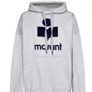 Grå hoodie från Isabel Marant - Säljer en stilren grå oversized hoodie från Isabel Marant med en stor logotyp i mörkblått framtill. Tröjan har en klassisk känguruficka och justerbar huva med dragsko. Perfekt för en avslappnad look.