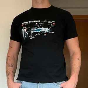 Svart vintage T-shirt - Svart t-shirt från SOL'S med Tour du Mont-Blanc-tryck på bröstet. Klassisk passform, rund hals och korta ärmar. Materialet är mjuk bomull som känns skönt mot huden. Perfekt för dig som gillar äventyr och coola grafiska prints.