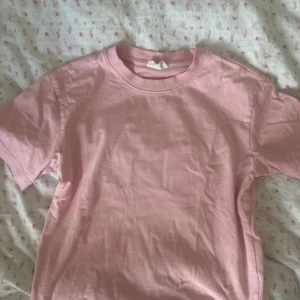 Rosa t-shirt från Gina Tricot - Enkel och stilren rosa t-shirt från Gina Tricot. T-shirten har rund halsringning och korta ärmar. Perfekt att matcha med jeans eller kjol för en clean look.