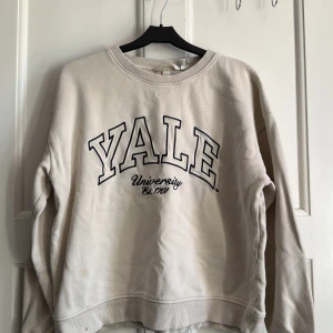  Yale sweatshirt från H&M - sweatshirt från H&M med stor svart YALE University-tryck på bröstet. Tröjan har rund hals, ribbade muddar och är i mjuk bomullsblandning. Perfekt för en chill och avslappnad stil. Långärmad och normal passform.