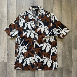 H&M svart och brun mönstrad skjorta - Kortärmad skjorta från H&M i storlek M. Modellen är 167 cm lång och väger 63 kg. Längden är 78 cm och axeln är 45 cm.