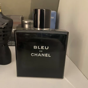 Bleu de Chanel Eau de toilette - En elegant och tidlös herrparfym från Chanel. Flaskan är fyrkantig och mörkblå med silverfärgad text och svart lock. Doften är träig och aromatisk, perfekt för dig som vill ha en klassisk och maskulin signaturdoft. Cirka 90ml kvar i flaskan. Nypris 1500