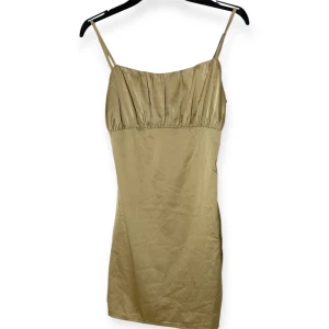 Gul kort klänning Missguided - Gul kort klänning från Missguided i glansigt satinliknande material. Smala axelband, rynkad överdel och figurnära passform. Dragkedja bak för enkel påklädning. Perfekt för dig som vill sticka ut med en elegant och trendig look. (Kolla sista bilden för att se den riktiga färgen)